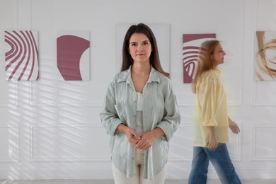 Photo of Woman in art gallery and people passing by, motion blur effect