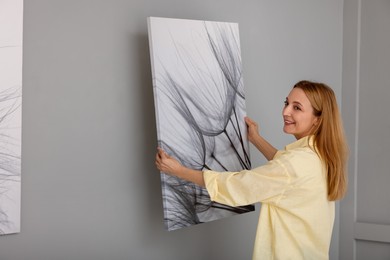 Woman hanging painting on wall in art gallery