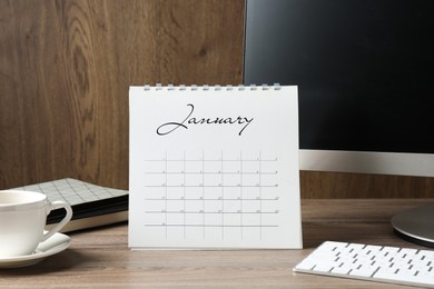 Photo of Timetable. Monthly planner, coffee, stationery and computer on wooden table