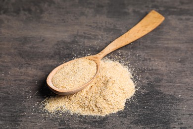 Photo of Oat bran in wooden spoon on grey table, closeup