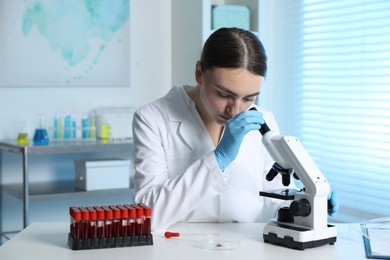 Photo of Laboratory testing. Doctor working with microscope at table indoors