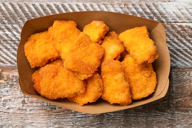 Photo of Delicious chicken nuggets on wooden table, top view