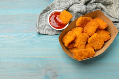 Photo of Delicious chicken nuggets with ketchup on blue wooden table, flat lay. Space for text