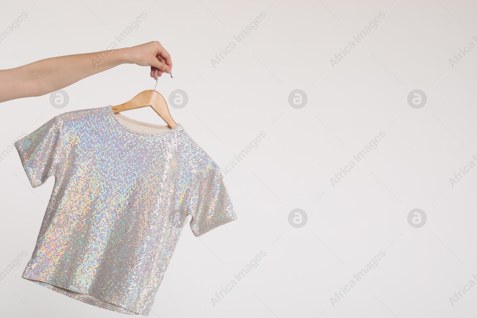 Photo of Woman holding hanger with t-shirt on white background, closeup