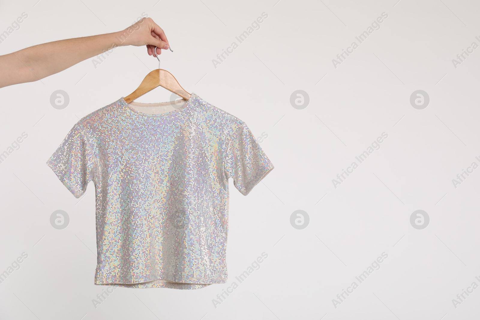 Photo of Woman holding hanger with t-shirt on white background, closeup