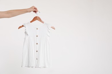 Photo of Woman holding hanger with baby dress on white background, closeup