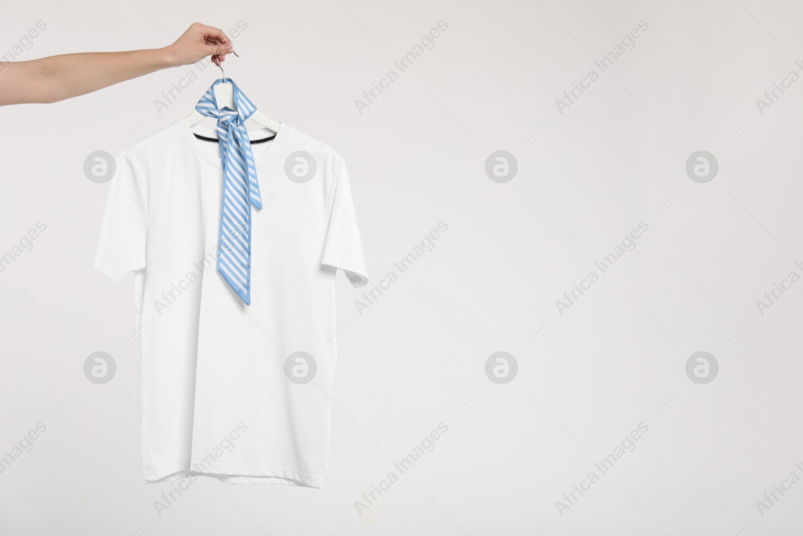 Photo of Woman holding hanger with t-shirt on white background, closeup