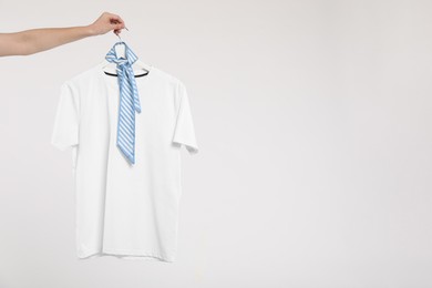 Photo of Woman holding hanger with t-shirt on white background, closeup