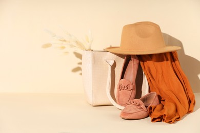 Photo of Clothes, shoes and bag on beige background, space for text