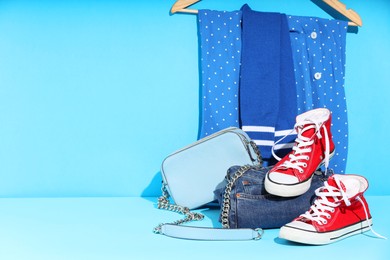 Photo of Clothes, shoes and bag on light blue background, space for text