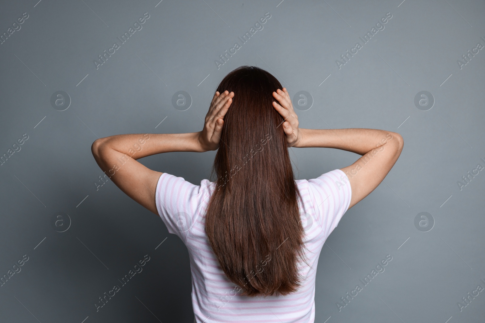 Photo of Woman covering her ears on grey background, back view