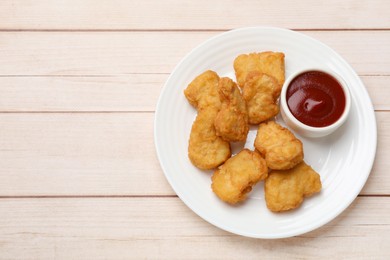 Photo of Delicious chicken nuggets and ketchup on wooden table, top view. Space for text