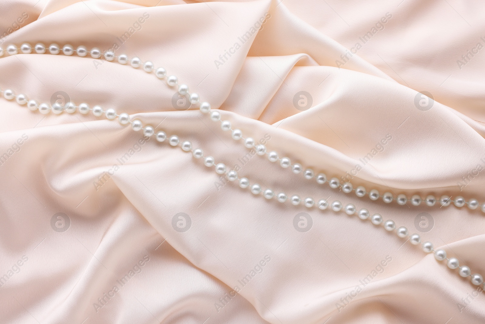 Photo of Beautiful pearl necklace on beige cloth, top view