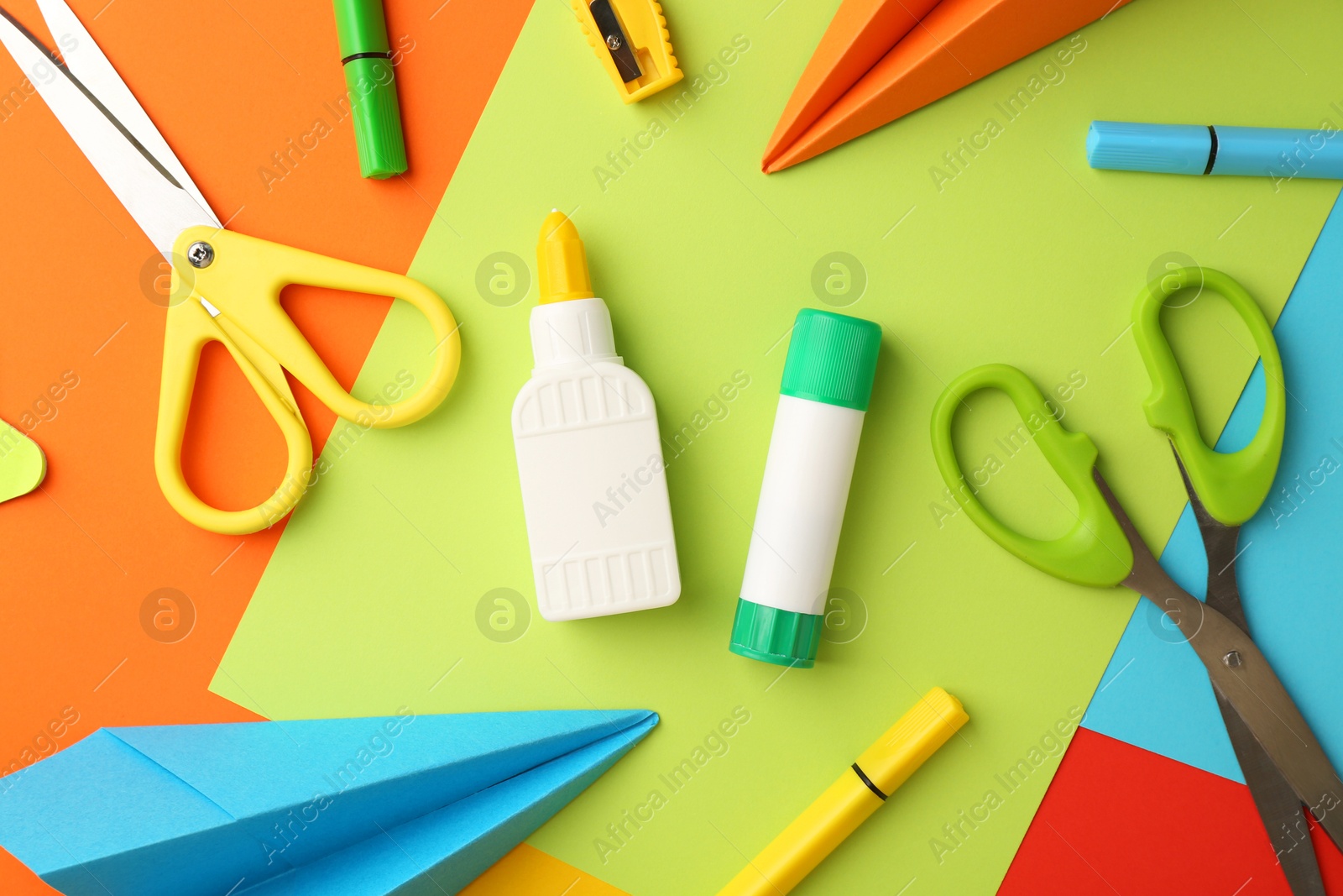 Photo of Flat lay composition with glue, scissors and other stationery on color background