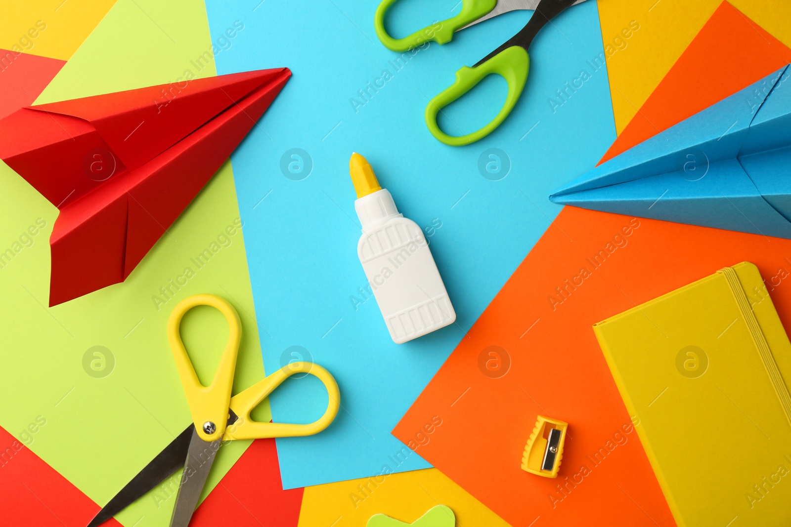 Photo of Flat lay composition with glue, scissors and other stationery on color background