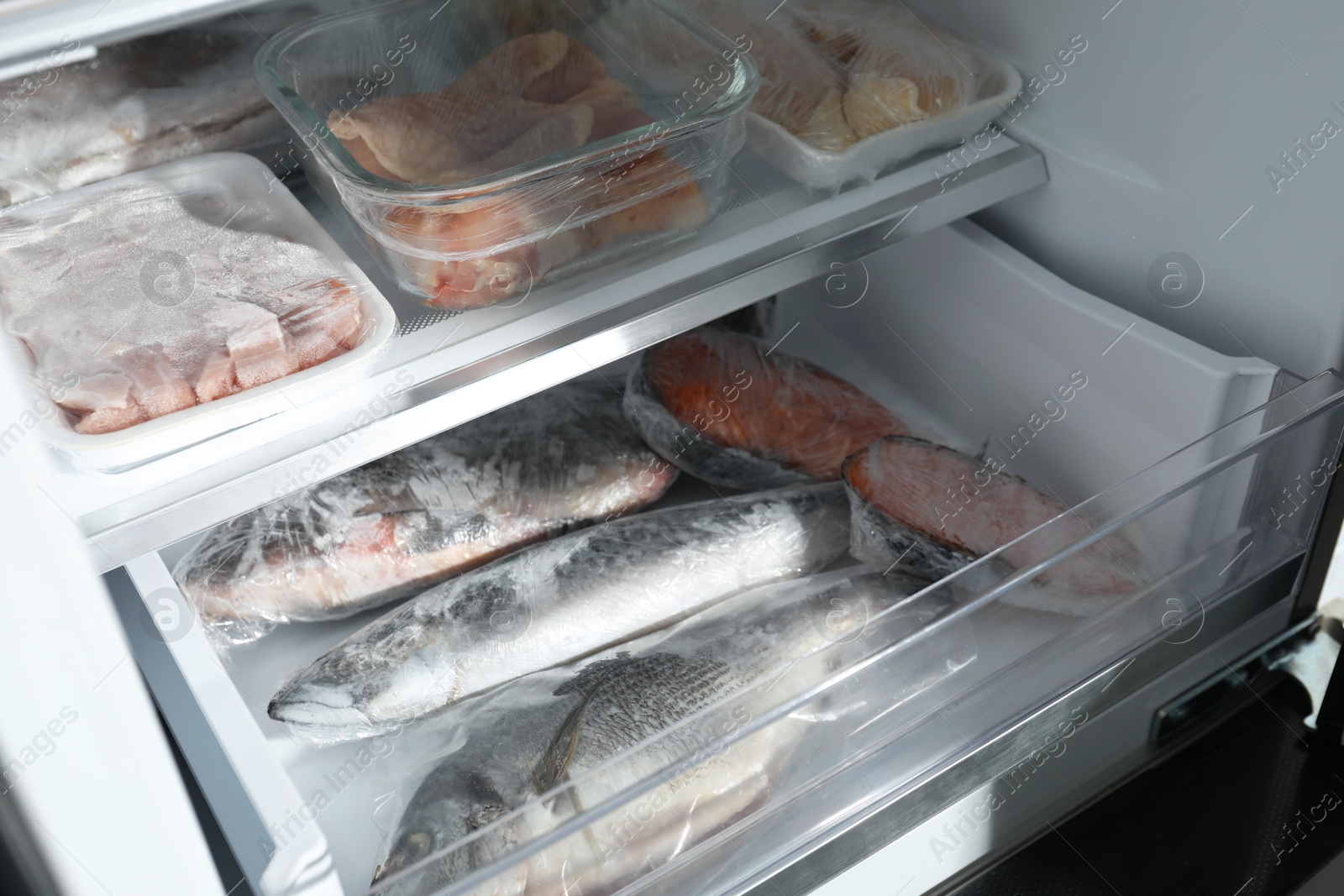 Photo of Different frozen meat and fish products in fridge, closeup