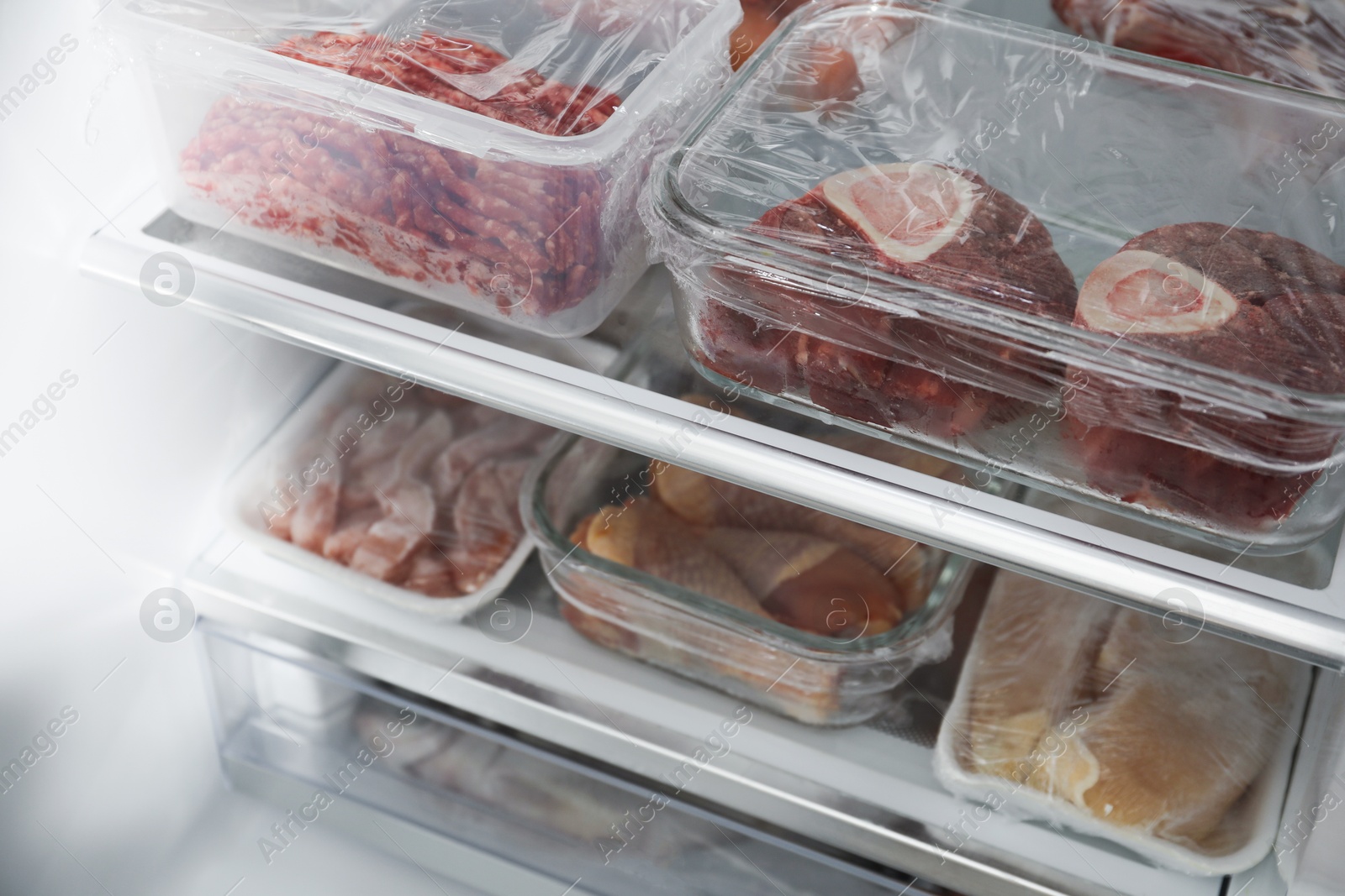 Photo of Different frozen meat products in fridge, closeup