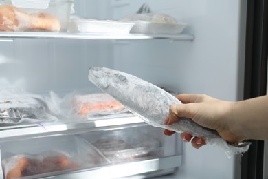 Photo of Woman taking frozen fish out of fridge, closeup