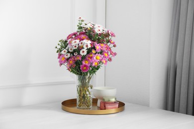 Photo of Beautiful flowers in vase and candles on white wooden table at home