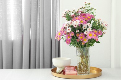 Photo of Beautiful flowers in vase and candles on white wooden table at home, space for text