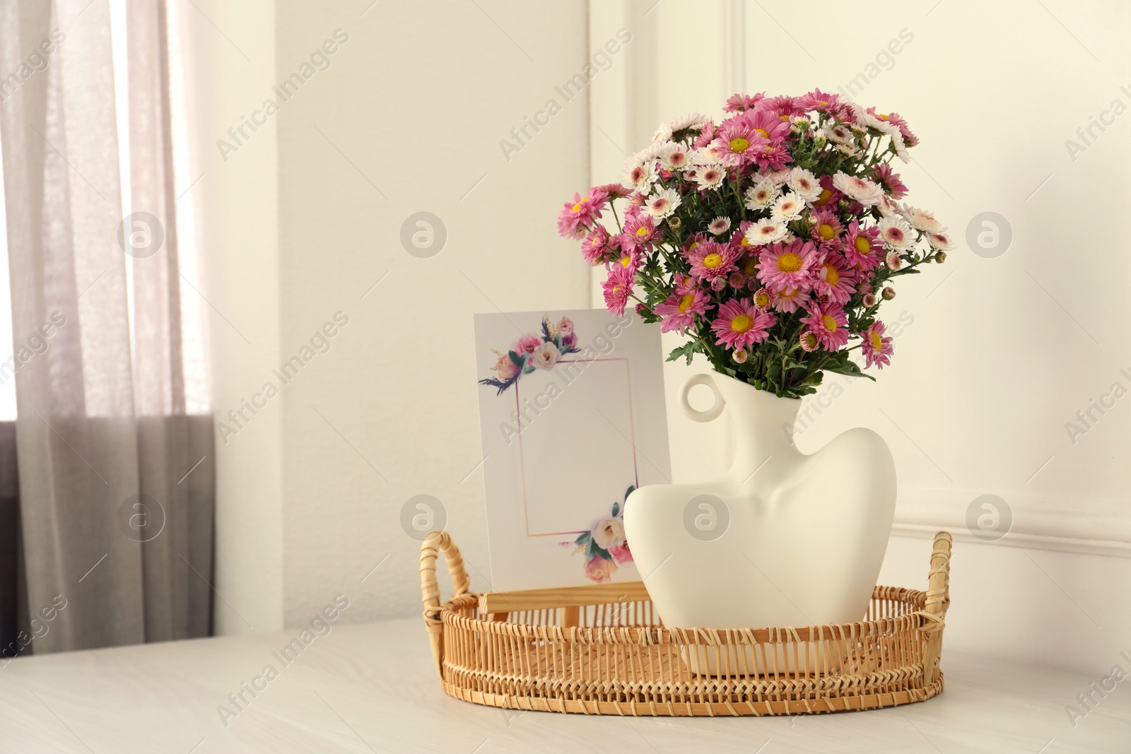 Photo of Stylish vase with beautiful flowers and decor on white wooden table at home