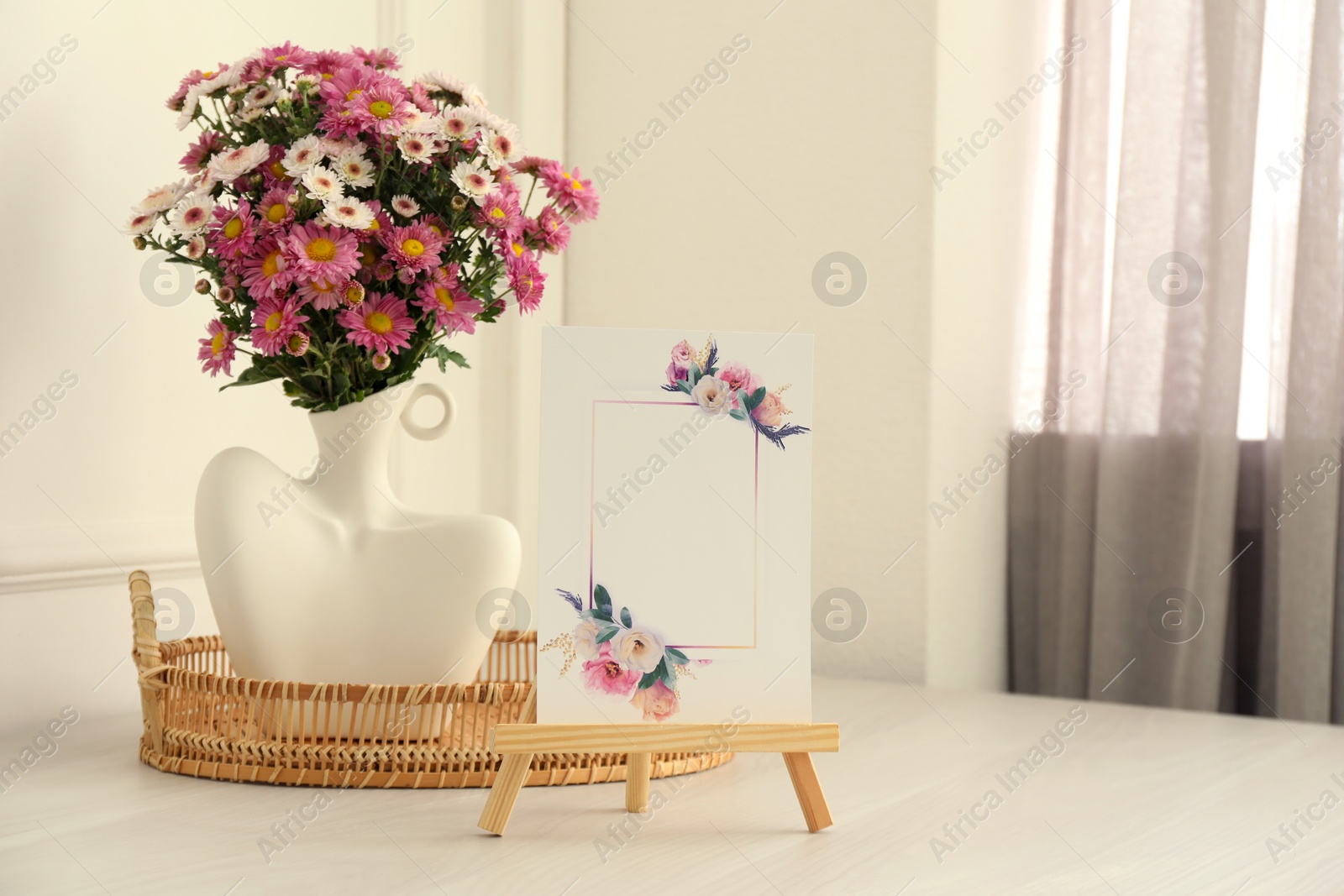 Photo of Stylish vase with beautiful flowers and decor on white wooden table at home