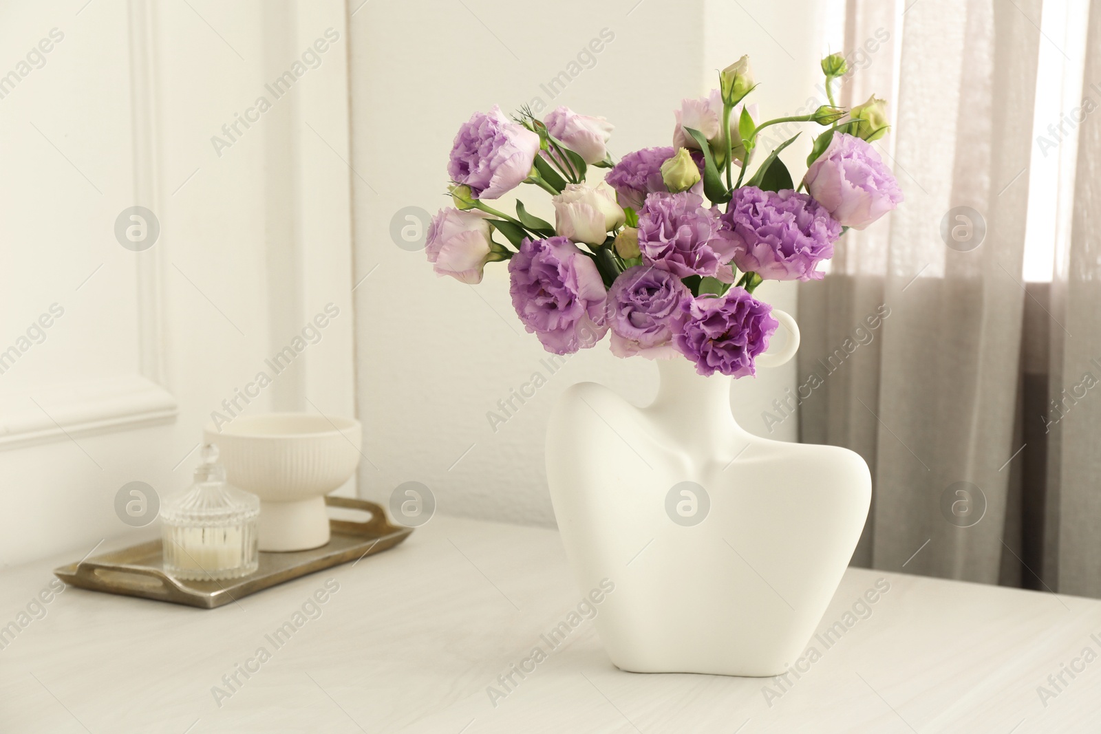 Photo of Stylish vase with beautiful flowers and decor on white wooden table at home