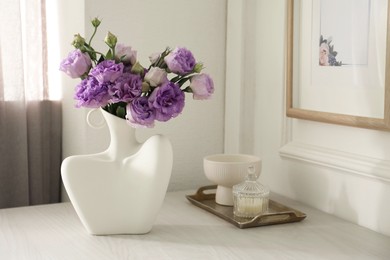 Photo of Stylish vase with beautiful flowers and decor on white wooden table at home