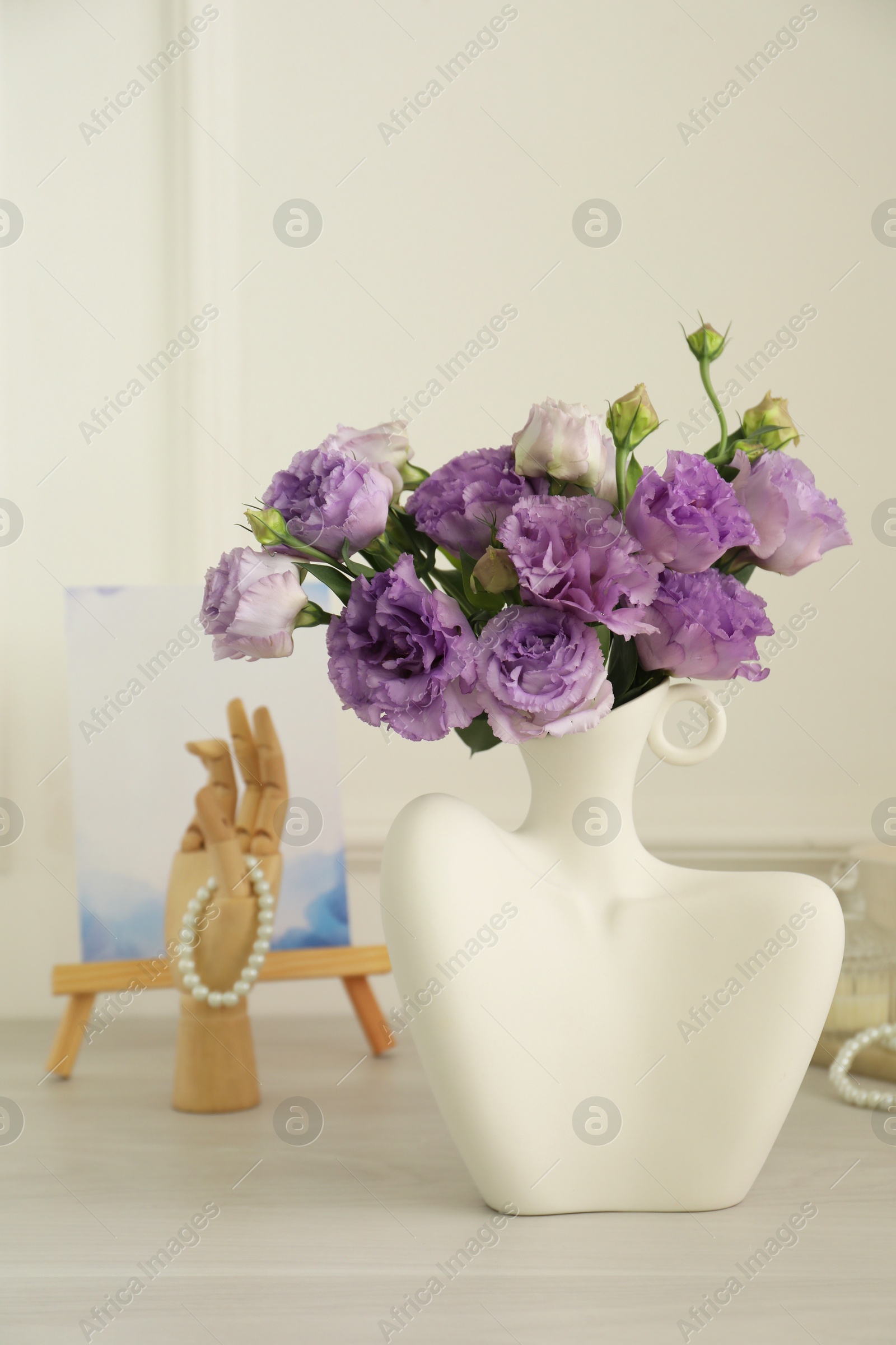 Photo of Stylish vase with beautiful flowers and decor on white wooden table at home