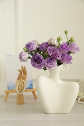 Photo of Stylish vase with beautiful flowers and decor on white wooden table at home