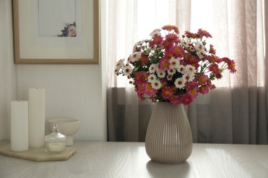 Photo of Beautiful flowers in vase and decor on white wooden table at home