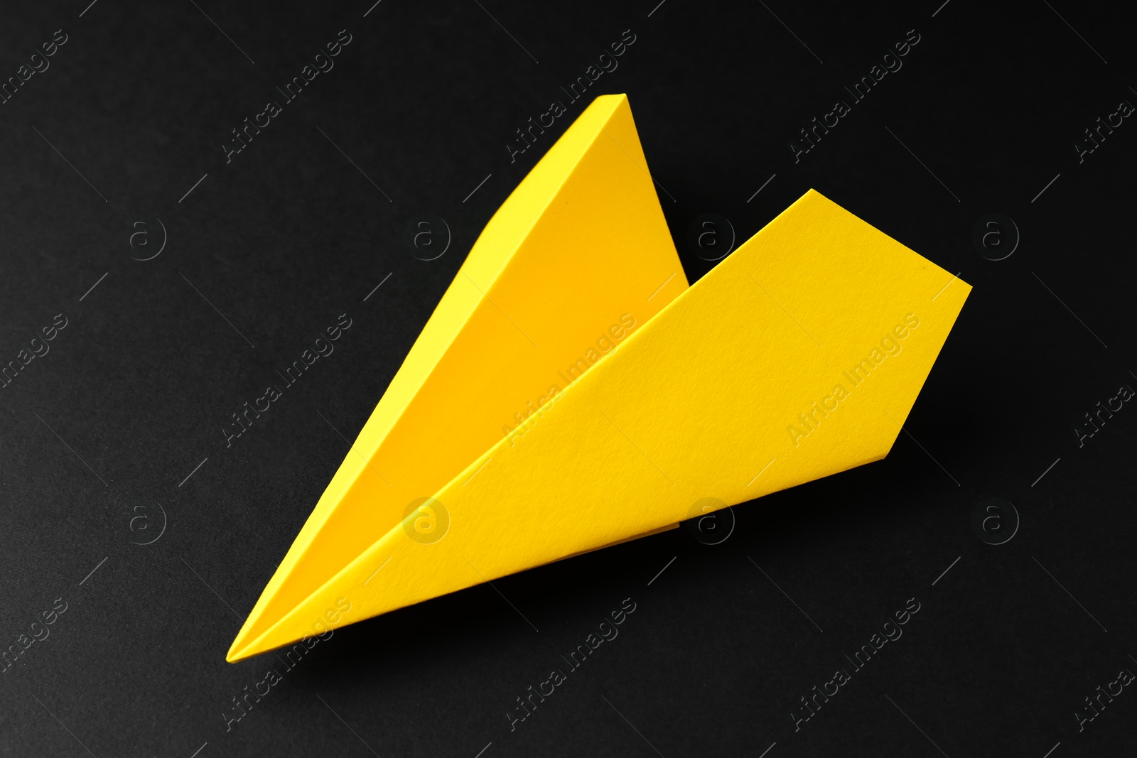 Photo of One handmade yellow paper plane on black background