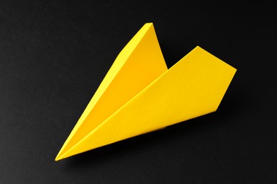 Photo of One handmade yellow paper plane on black background