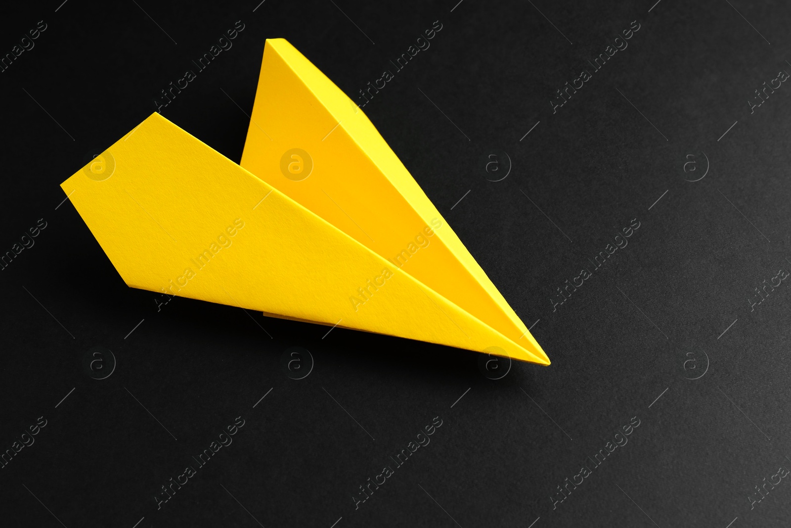 Photo of One handmade yellow paper plane on black background. Space for text