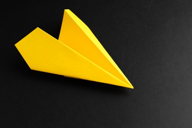 Photo of One handmade yellow paper plane on black background. Space for text