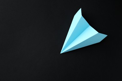 Photo of One handmade light blue paper plane on black background, top view. Space for text