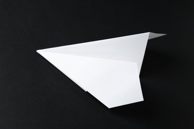 Photo of One handmade paper plane on black background, closeup