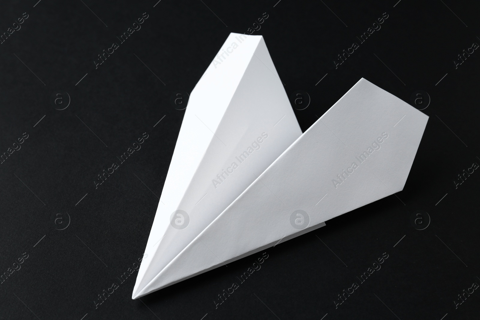 Photo of One handmade paper plane on black background, closeup