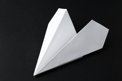 Photo of One handmade paper plane on black background, closeup