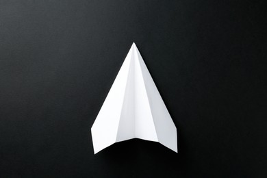 Photo of One handmade paper plane on black background, top view