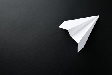 Photo of One handmade paper plane on black background, top view. Space for text