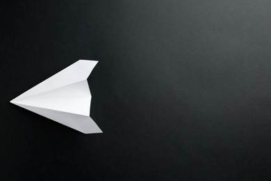 Photo of One handmade paper plane on black background, top view. Space for text