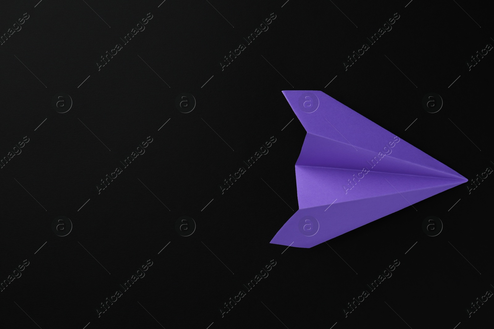 Photo of One handmade violet paper plane on black background, top view. Space for text