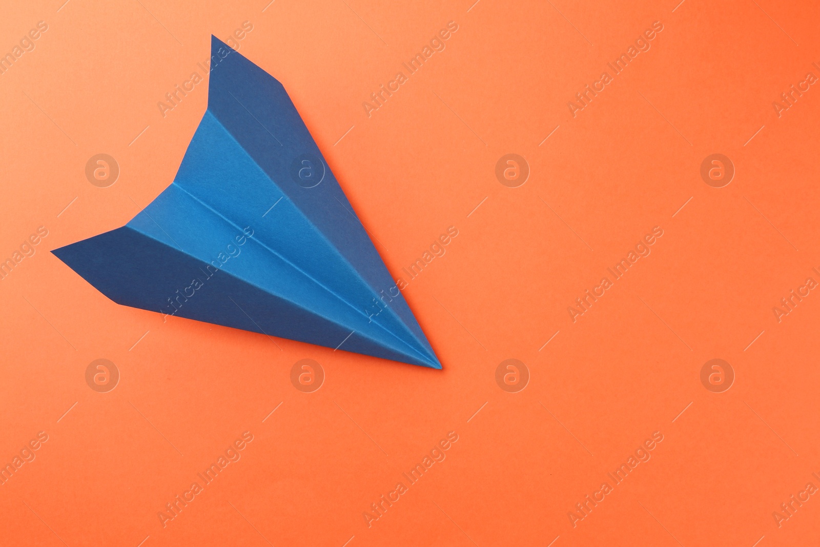 Photo of One handmade blue paper plane on orange background, top view. Space for text