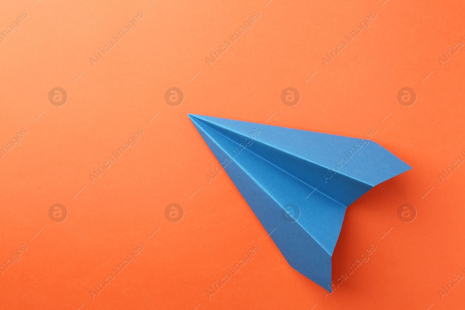 Photo of One handmade blue paper plane on orange background, top view. Space for text