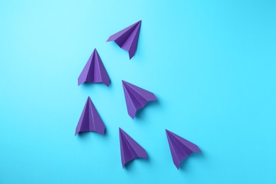 Photo of Handmade purple paper planes on light blue background, top view