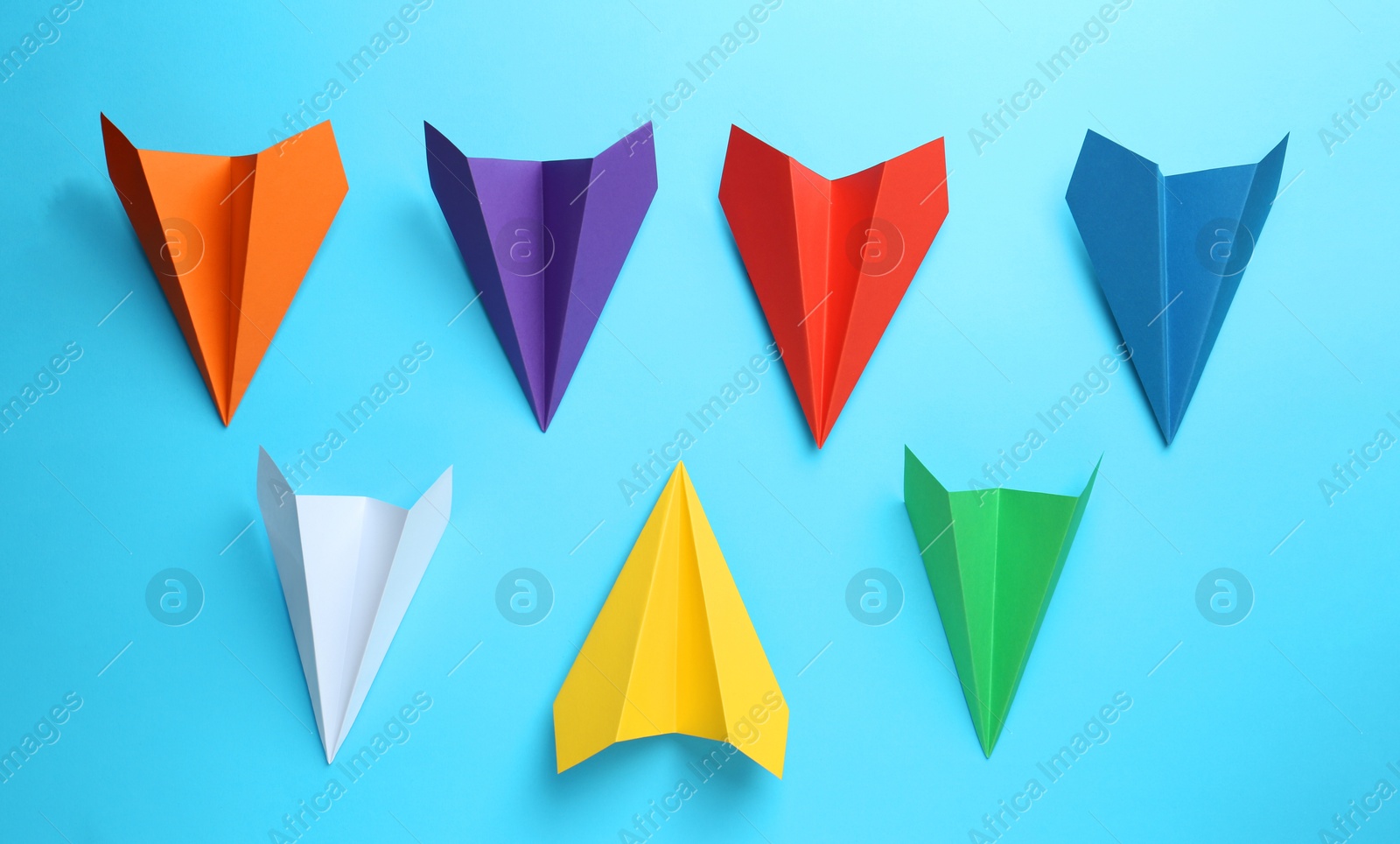 Photo of Handmade color paper planes on light blue background, flat lay