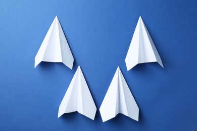 Photo of Handmade paper planes on blue background, top view