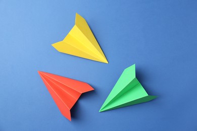 Photo of Handmade color paper planes on blue background, flat lay