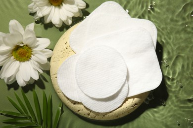 Photo of Flat lay composition with cotton pads on wet green surface